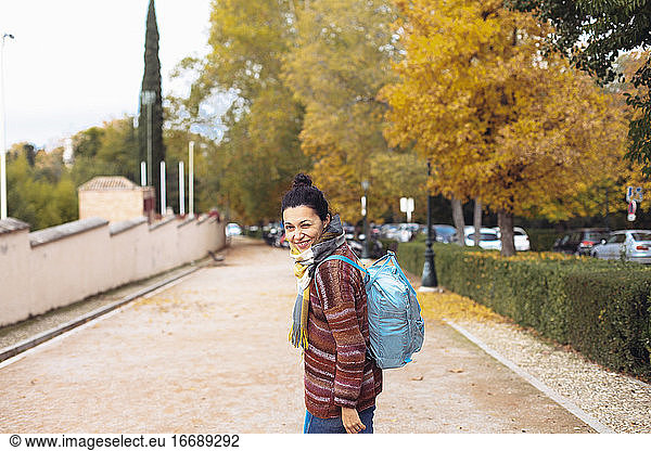 Young woman with a backpack walking on the street  autumn
