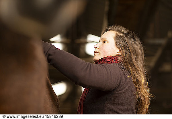 young woman with a horse in a horse stable
