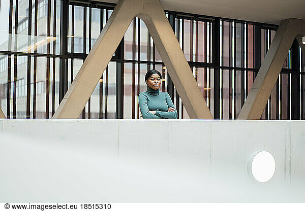 Young woman with arms crossed standing near railing