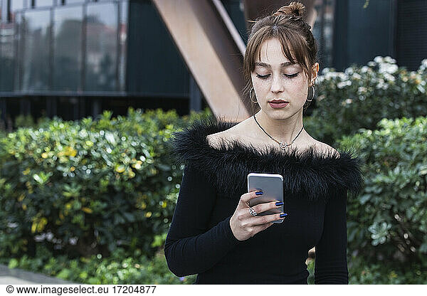 Young woman with bangs using smart phone