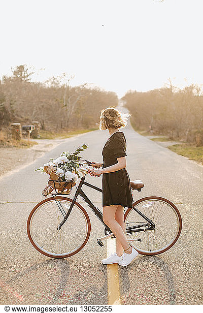 Young woman with bicycle looking sideways on rural road  Menemsha  Martha's Vineyard  Massachusetts  USA