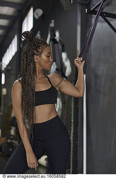 Young woman with braided hair exercising with resistance band in gym