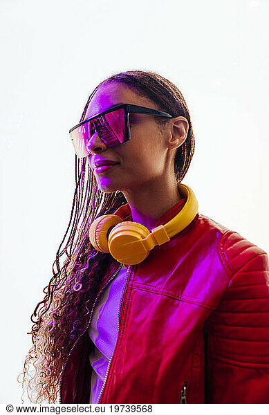 Young woman with braided hair wearing sunglasses and headphones in tunnel