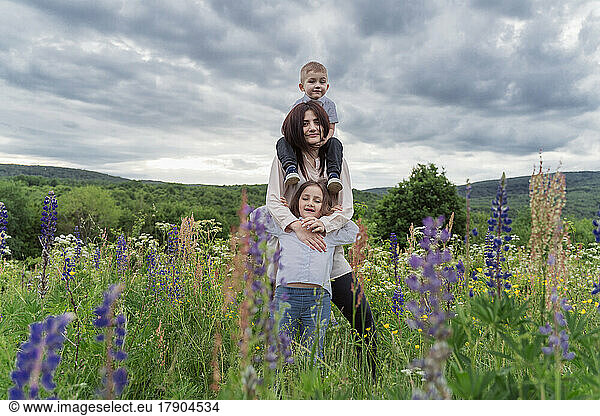 Young woman with children in wildflowers meadow