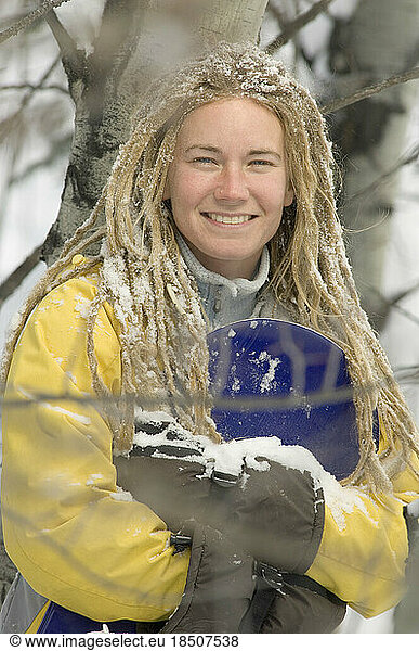 Young woman with dreadlocks holding snowboard.