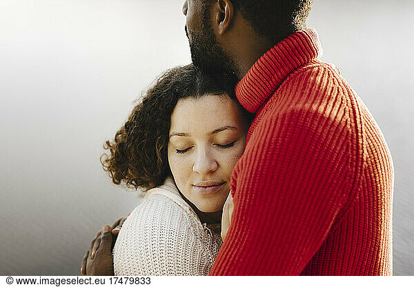 Young woman with eyes closed embracing boyfriend