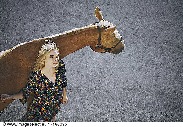 Young woman with eyes closed standing against horse