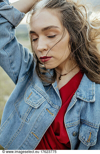 Young woman with eyes closed wearing denim jacket
