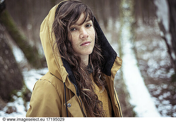 Young woman with freckles and long curly hair in winter snow jacket