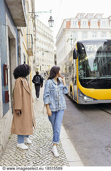 Young woman with friend looking at bus