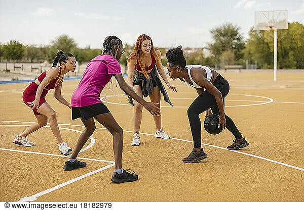 Young woman with friends playing basketball at sports court