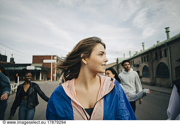 Young woman with friends walking on street in city