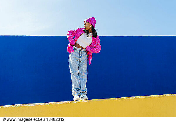 Young woman with hand on hip dancing on wall