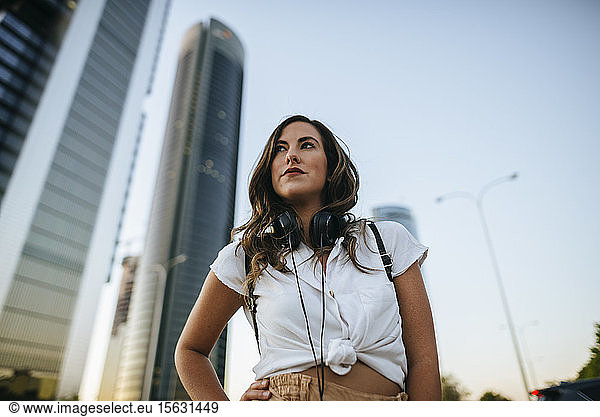 Young woman with headphones around neck  skyscrapers in the background