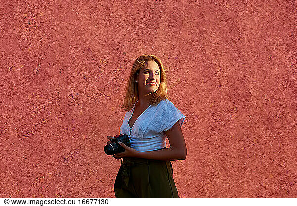 Young woman with her camera on a red background