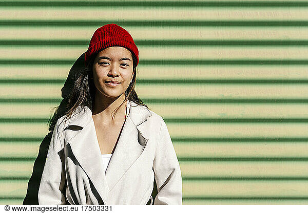 Young woman with knit hat in front of corrugated wall