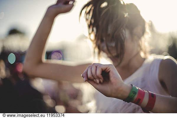 Young woman with long brown hair at a summer music festival dancing.