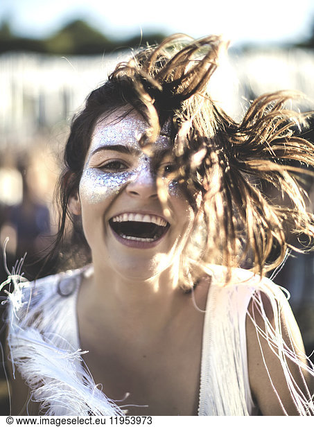 Young woman with long brown hair at a summer music festival face painted  smiling at camera.