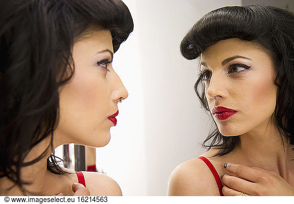 Young woman with nose piercing looking in mirror