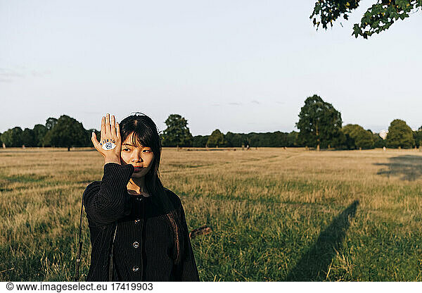 Young woman with painted hand standing at park during sunny day