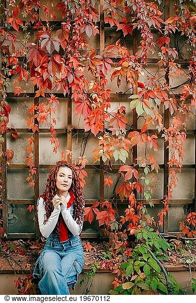 Young woman with red hair in autumn leaves in Prague
