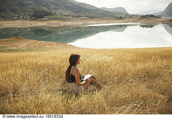 Young woman with sketch pad sitting in front of Rama Lake