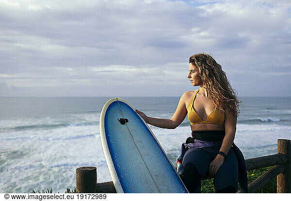 Young woman with surfboard contemplating near sea