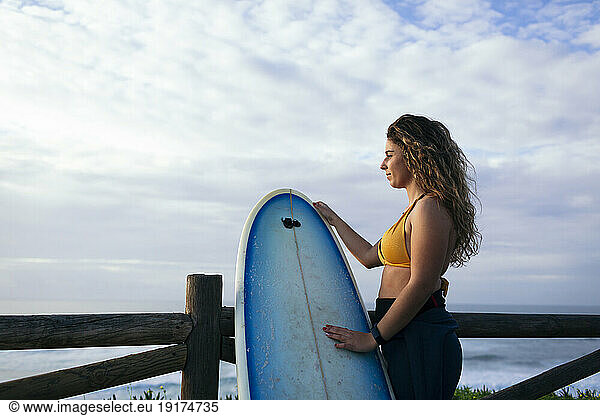Young woman with surfboard looking at sea