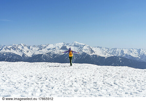 Young woman with yellow backpack running in snowy mountains