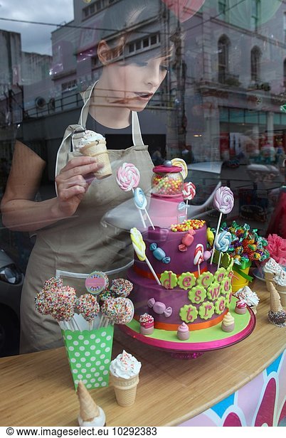 Young woman working in cake shop  arranging window display