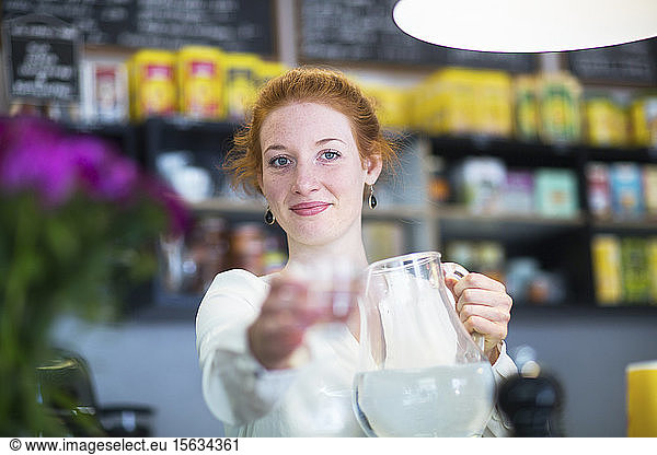Young woman working in coffee shop  giving a water glass
