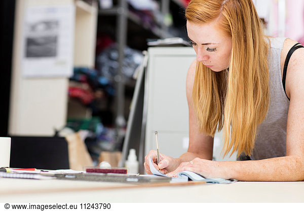 Young woman working in leather jacket manufacturers  close-up