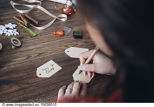 Young woman writing Christmas gift tags
