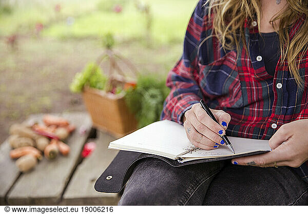 Young woman writing in diary with pen