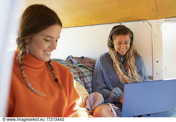 Young women friends using laptop in camper van