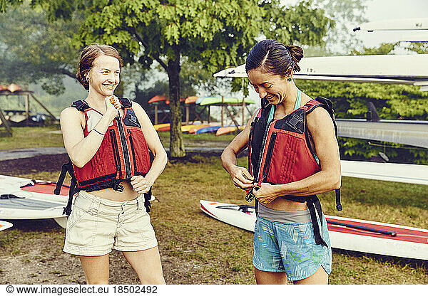 Young women put on their life jackets in preparation for kayak trip