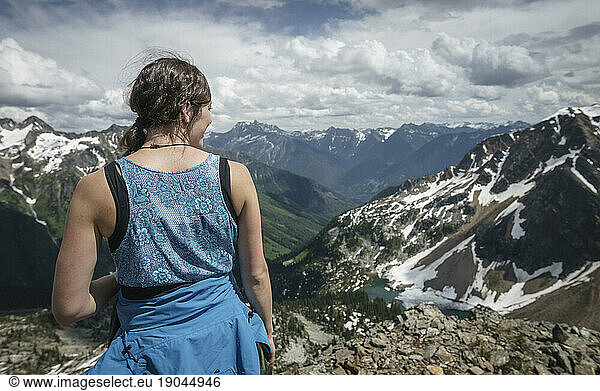 Young women stands  looking at mountain and lake with a cloudy sky  BC