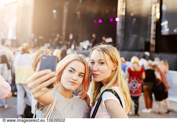 Young women taking self portrait on smartphone