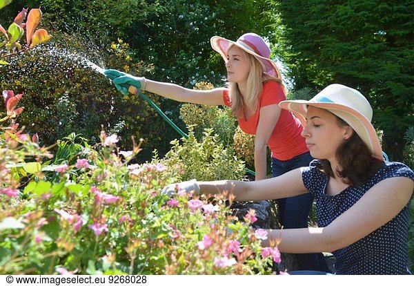 Young women watering garden with hosepipe