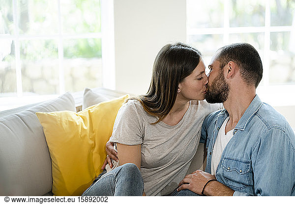 Zärtliches junges verliebtes Paar  das sich zu Hause auf der Couch küsst