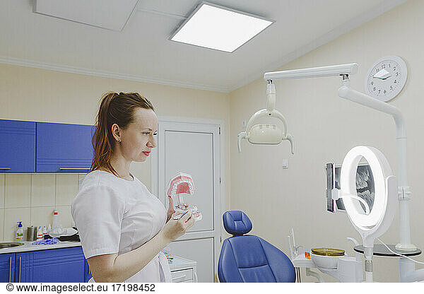 Zahnärztin zeigt Zahnersatz in Richtung Live-Streaming-Smartphone