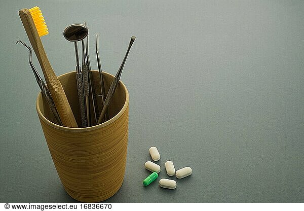 Zahnarztwerkzeug in einem Sockel und einige Tabletten.