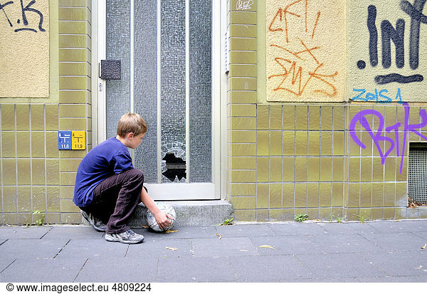 Zehnjähriger Junge betrachtet die eingeschossene Glasscheibe einer Haustür  Deutschland  Europa