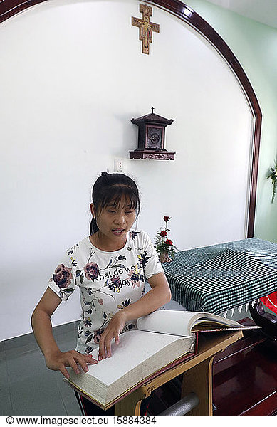 Zentrum für blinde Kinder  das von Children Action betrieben wird. Katholische Kapelle. Ein blindes Mädchen liest eine Bibel in Blindenschrift. Ho Chi Minh Stadt. Vietnam.
