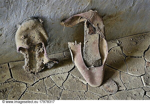 Zerfallene rosa Damenschuhe auf Lehmboden  Schwarzer Lachschuh mit Schleife für Damen  verrotteter Schuh  Schuhwrack  vergammelter Treter  ausgelatschter Schuh  abgetragener Schuh