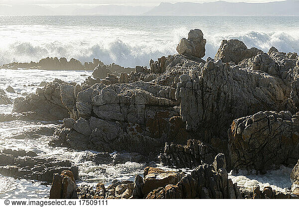 Zerklüftete Felsen am Ufer von De Kelders  hohe Wellen rollen heran und brechen sich an den Felsen
