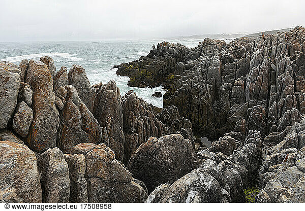 Zerklüftete Felsen und die felsige Küste des Atlantiks am Strand von De Kelders  Wellen  die sich am Ufer brechen.