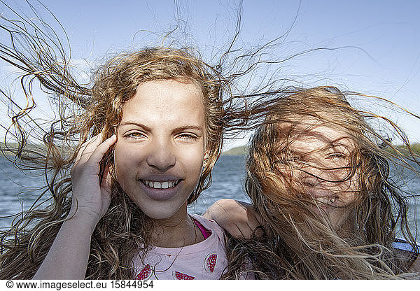 Zerzauste Haarzwillinge lächeln bei starkem Sturm