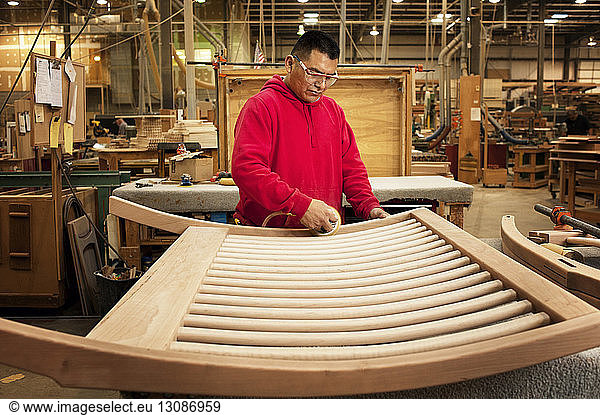 Zimmermann poliert geschnitztes Holz in der Werkstatt