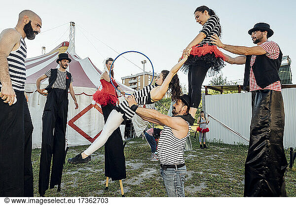 Zirkusakrobaten und Artisten üben miteinander hinter dem Zirkuszelt